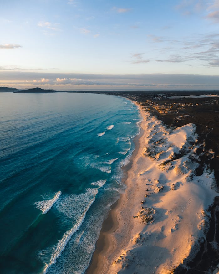 Stunning aerial panorama of Cabo Frio, Brazil's pristine beaches and vibrant ocean waves at sunrise.