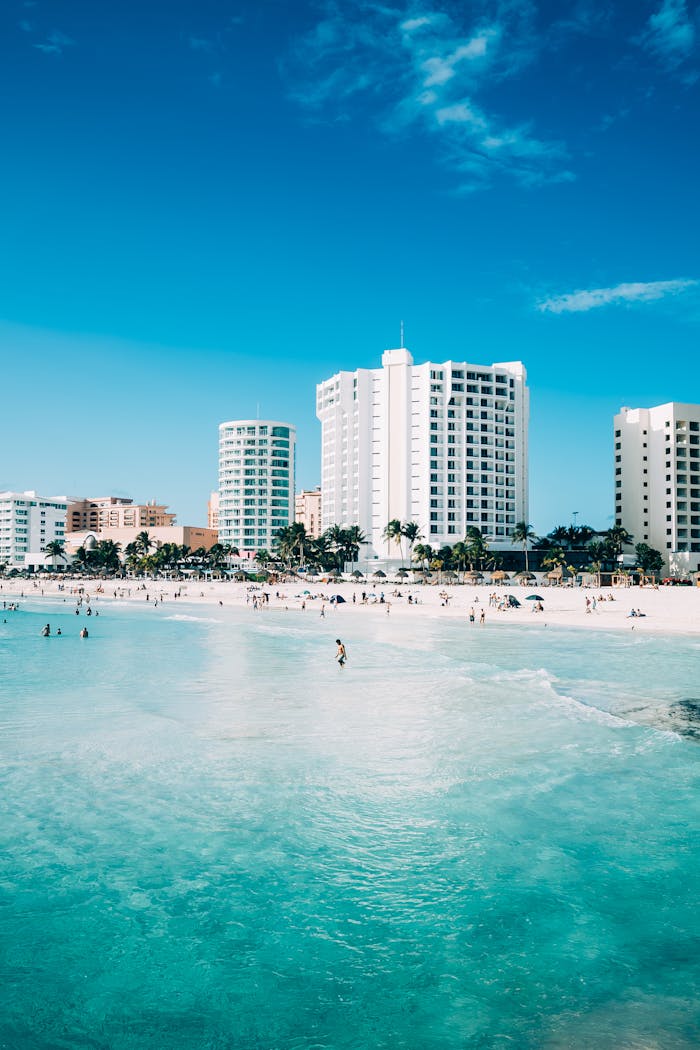 about-01 Scenic view of modern hotels along the beachfront in Cancun, Mexico, with clear blue waters.