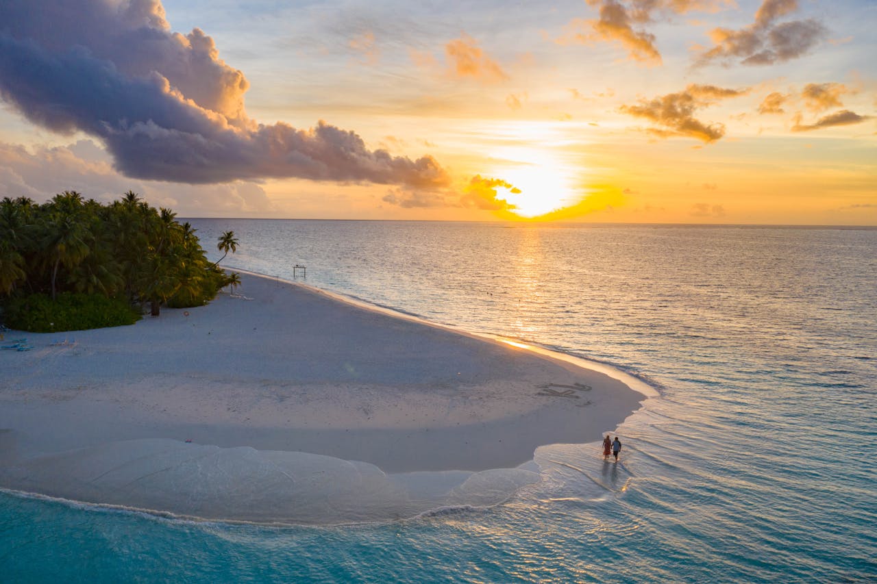 why-choose-us A couple enjoys a serene sunset on a pristine Maldives beach.